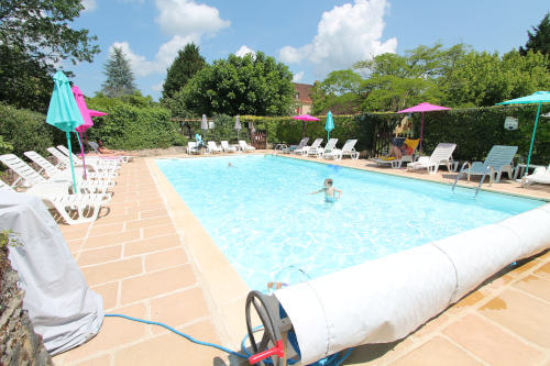 swimming pool with swimmers and sun loungers